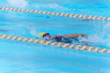 Yüzücü çocuk yüzme havuzunda sırt üstü yüzer. Su sporları ve yarışma, çocuklar için yüzme dersleri..