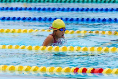 Yüzücü çocuk yüzme havuzunda kurbağalama yüzme stili yüzer. Su sporları ve yarışma, çocuklar için yüzme dersleri.