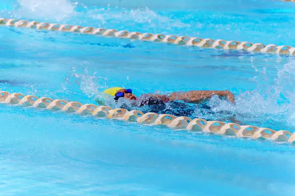Yüzücü çocuk yüzme havuzunda sırt üstü yüzer. Su sporları ve yarışma, çocuklar için yüzme dersleri..