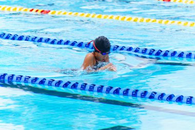 Yüzücü çocuk yüzme havuzunda kurbağalama yüzme stili yüzer. Su sporları ve yarışma, çocuklar için yüzme dersleri.