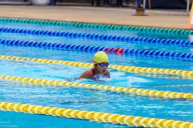 Yüzücü çocuk yüzme havuzunda kurbağalama yüzme stili yüzer. Su sporları ve yarışma, çocuklar için yüzme dersleri.