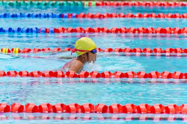 Yüzücü çocuk yüzme havuzunda kurbağalama yüzme stili yüzer. Su sporları ve yarışma, çocuklar için yüzme dersleri.