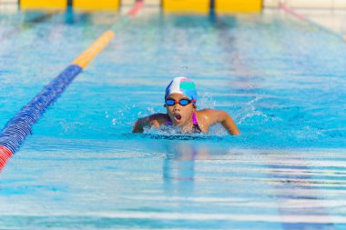 Yüzücü çocuk yüzme havuzunda kelebek yüzme stili yüzer. Su sporları ve yarışma, çocuklar için yüzme dersleri..