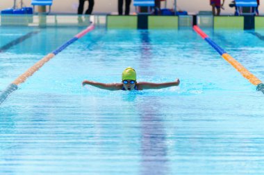 Yüzücü çocuk yüzme havuzunda kelebek yüzme stili yüzer. Su sporları ve yarışma, çocuklar için yüzme dersleri..