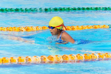 Yüzücü çocuk yüzme havuzunda kurbağalama yüzme stili yüzer. Su sporları ve yarışma, çocuklar için yüzme dersleri..