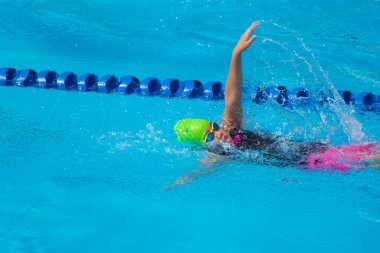 Yüzücü çocuk yüzme havuzunda sırt üstü yüzer. Su sporları ve yarışma, çocuklar için yüzme dersleri..
