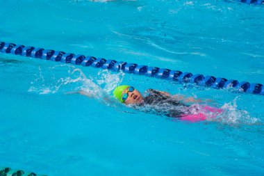 Yüzücü çocuk yüzme havuzunda sırt üstü yüzer. Su sporları ve yarışma, çocuklar için yüzme dersleri..