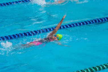 Yüzücü çocuk yüzme havuzunda sırt üstü yüzer. Su sporları ve yarışma, çocuklar için yüzme dersleri..