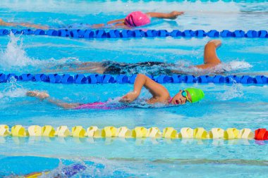 Yüzücü çocuk yüzme havuzunda serbest yüzme stili yüzer. Su sporları ve yarışma, çocuklar için yüzme dersleri.