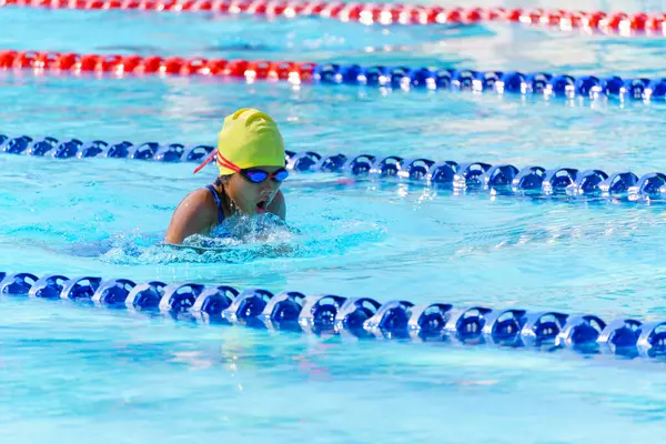 Yüzücü çocuk yüzme havuzunda kurbağalama yüzme stili yüzer. Su sporları ve yarışma, çocuklar için yüzme dersleri..