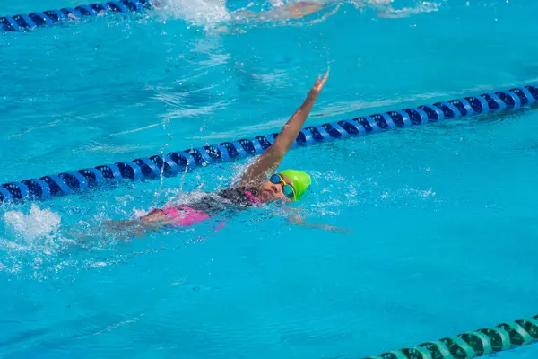 Yüzücü çocuk yüzme havuzunda sırt üstü yüzer. Su sporları ve yarışma, çocuklar için yüzme dersleri..