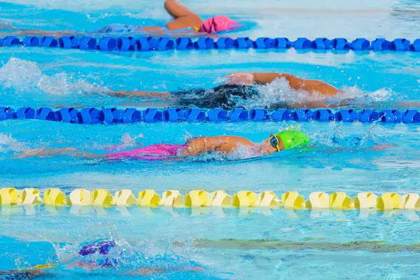 Yüzücü çocuk yüzme havuzunda serbest yüzme stili yüzer. Su sporları ve yarışma, çocuklar için yüzme dersleri.