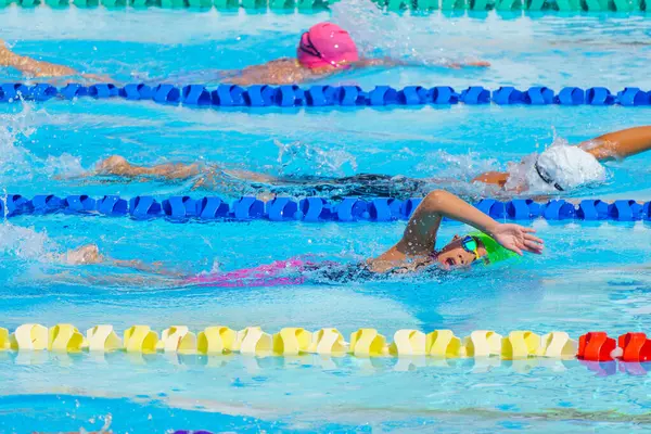 Yüzücü çocuk yüzme havuzunda serbest yüzme stili yüzer. Su sporları ve yarışma, çocuklar için yüzme dersleri..
