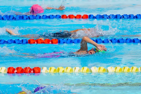 Yüzücü çocuk yüzme havuzunda serbest yüzme stili yüzer. Su sporları ve yarışma, çocuklar için yüzme dersleri..