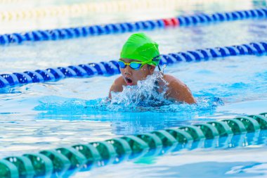 Yüzücü çocuk yüzme havuzunda kurbağalama yüzme stili yüzer. Su sporları ve yarışma, çocuklar için yüzme dersleri.