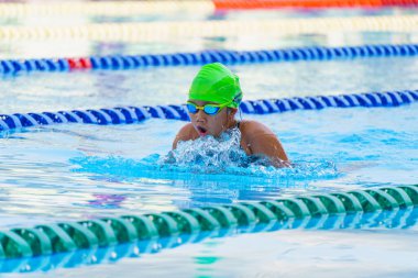 Yüzücü çocuk yüzme havuzunda kurbağalama yüzme stili yüzer. Su sporları ve yarışma, çocuklar için yüzme dersleri.