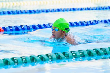 Yüzücü çocuk yüzme havuzunda kurbağalama yüzme stili yüzer. Su sporları ve yarışma, çocuklar için yüzme dersleri.