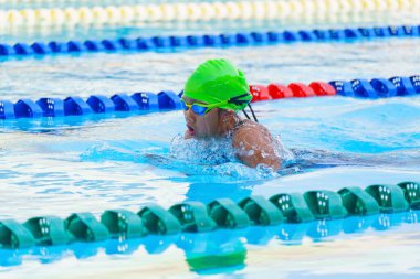 Yüzücü çocuk yüzme havuzunda kurbağalama yüzme stili yüzer. Su sporları ve yarışma, çocuklar için yüzme dersleri.