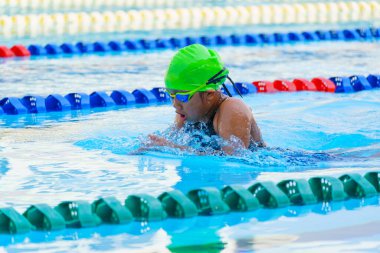 Yüzücü çocuk yüzme havuzunda kurbağalama yüzme stili yüzer. Su sporları ve yarışma, çocuklar için yüzme dersleri.
