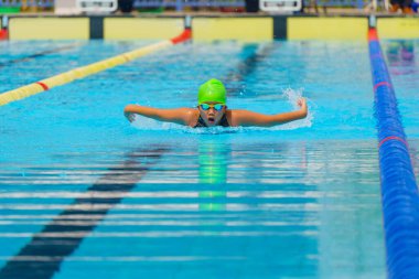 Yüzücü çocuk yüzme havuzunda kelebek yüzme stili yüzer. Su sporları ve yarışma, çocuklar için yüzme dersleri..