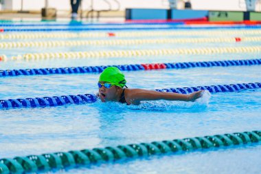 Yüzücü çocuk yüzme havuzunda kelebek yüzme stili yüzer. Su sporları ve yarışma, çocuklar için yüzme dersleri..