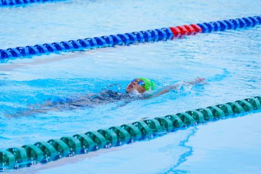 Yüzücü çocuk yüzme havuzunda sırt üstü yüzer. Su sporları ve yarışma, çocuklar için yüzme dersleri..