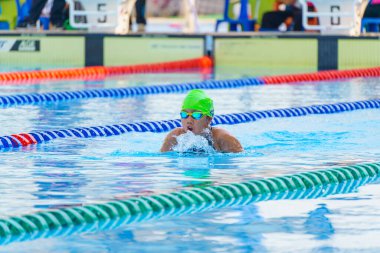 Yüzücü çocuk yüzme havuzunda kurbağalama yüzme stili yüzer. Su sporları ve yarışma, çocuklar için yüzme dersleri.