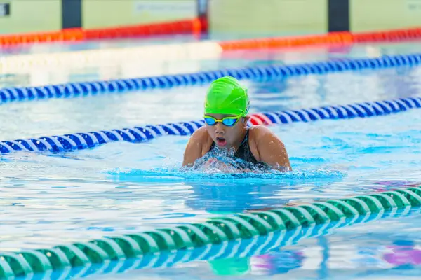 Yüzücü çocuk yüzme havuzunda kurbağalama yüzme stili yüzer. Su sporları ve yarışma, çocuklar için yüzme dersleri.