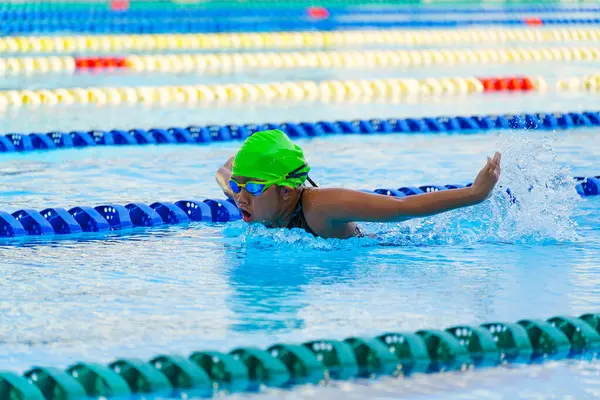 Yüzücü çocuk yüzme havuzunda kelebek yüzme stili yüzer. Su sporları ve yarışma, çocuklar için yüzme dersleri..