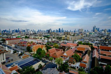 Bangkoks geleneksel kırmızı çatı tapınaklarını gösteren geniş bir şehir manzarası canlı mavi gökyüzü ve modern gökyüzü