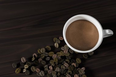 Kahverengi kahveyle dolu, koyu ahşap bir masada kavrulmuş kahve çekirdekleri ile çevrili beyaz bir kahve fincanı. Kafe, marka veya ürün tasarımı için minimalist kompozisyon ideal