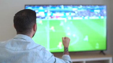 Mutlu futbol fanatiği evde bulanık televizyon izleyerek golü kutluyor. Yüksek kalite 4k görüntü