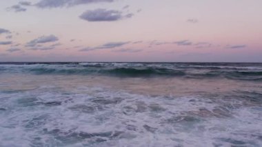 Dalgaların yavaş bir şekilde çarptığı harika sahil gün batımı. Yüksek kalite 4k görüntü