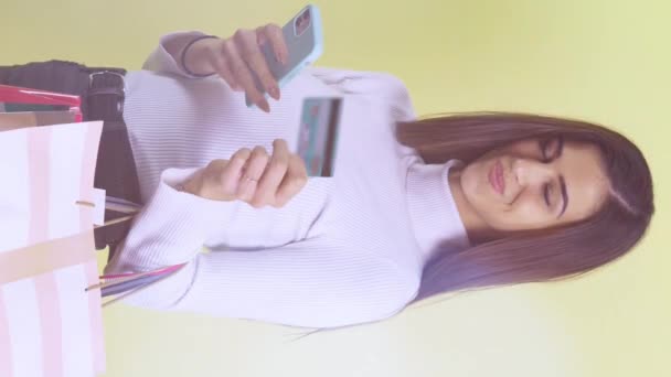 Piękna Szczęśliwa Kobieta Kartą Kredytową Torbami Zakupy Izolowane Żółtym Tle — Wideo stockowe