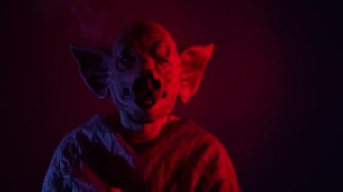 Yeşil ekran akıllı telefon tutan domuz maskeli korkunç bir adam. Cape 'li psikopat, elinde akıllı telefon tutuyordu. Stüdyonun arka planında yeşil ekran vardı. Yüksek kalite 4k görüntü