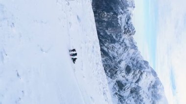 drone flys over group of hikers tourists on snowy mountain top nature background. extreme hiking winter recreation . High quality FullHD footage