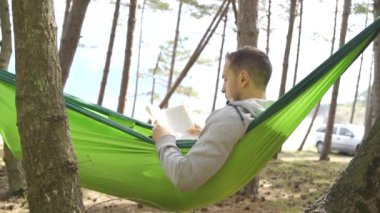 young man enjoy holiday reading in camping near trees and tents black sea. High quality FullHD footage