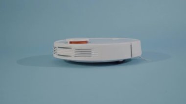close up of robot vacuum cleaner isolated in studio with blue background. High quality 4k footage