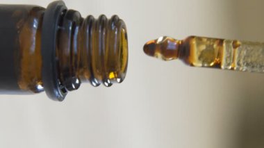macro shot of cbd Droplets of Hemp oil filling Dropper Bottle vertical video. High quality FullHD footage