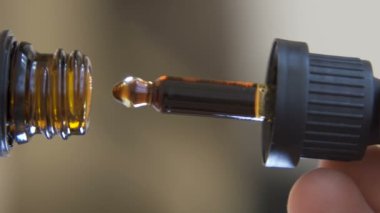 macro shot of male hand take Droplets of cbd oil filling Dropper glass Bottle, vertical video. High quality FullHD footage