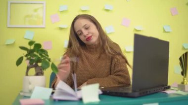  Kafkasyalı bir iş kadını dizüstü bilgisayarı üzerinde çalışırken sıkılmış ve bitkin görünüyor, yorgunluk ve motivasyon eksikliği gösteriyor. Ofis yangınını ve ilgisizliği tasvir etmek için ideal.