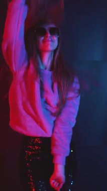 Kırmızı ve mavi ışıkların altında dans eden bir kadının stilize edilmiş görüntüsü. Onun figürü gölgeler ve renkler arasında hareket eder, sanatsal ya da editörlük için anlamlı ve atmosferik bir performans yaratır.