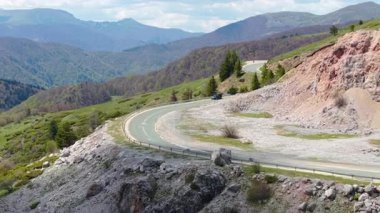 Uçsuz bucaksız bahar manzarasına karşı arabanın sinematik hareketi seyahat, yol gezileri ve açık hava maceraları için mükemmel bir görüntü sunuyor..
