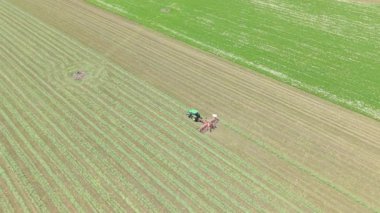 Gelişmiş bir tarım makinesinin canlı, taze bir buğday tarlasında özenle çalışan dinamik hava görüntüsü. Ağır makineler toprağı rahatça dolaşır, hasat eder ya da