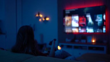 Genç bir kadın evde yalnız başına huzurlu bir film gecesinin tadını çıkarıyor, patlamış mısır yiyor, rahat ve sakin bir akşam atmosferinde kanepede dinleniyor..
