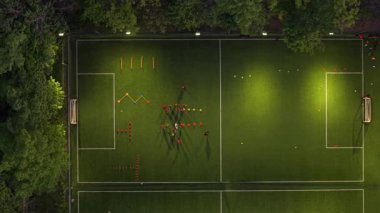 Şehir parkındaki futbol maçının en üst görüntüsü yeşil ağaçlar ve şehirle harmanlanan doğa ile çevrili.