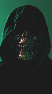 Çevrimiçi suç ve dijital gözetleme kavramı, maskeli adam karanlık ortamda doğrudan kameraya bakıyor.