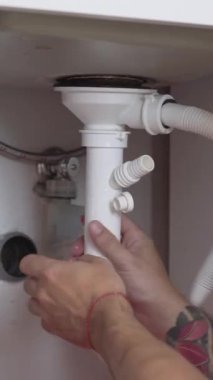 Profesyonel tesisatçı tarafından mutfak lavabosunun altına yerleştirilen yeni sifonun dikey dizilimi.