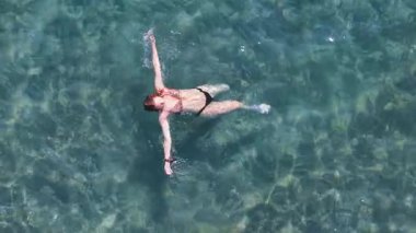 İnsansız hava aracı görüntüleri, Yunanistan 'ın Nikiti kıyısındaki turkuaz sularda yüzen genç bir kadının huzurlu bir anını yakalıyor. Yukarıdan mükemmel bir yaz sahnesi.