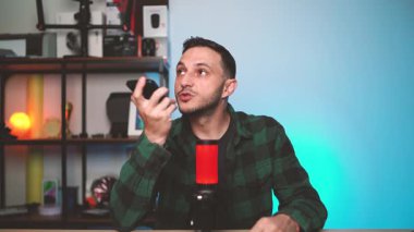 Bir adam telefonundaki yapay zeka asistanıyla iletişim kurmak için sesli komutlar kullanıyor, sakin bir ortamda yüzüne karşı tutuyor. Akıllı teknoloji ve ses kontrollü aygıtlar kavramı.